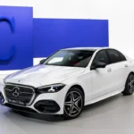 2027 Mercedes-Benz C-Class refreshed front three-quarter view with illuminated grille, AutoAkhbar branded image