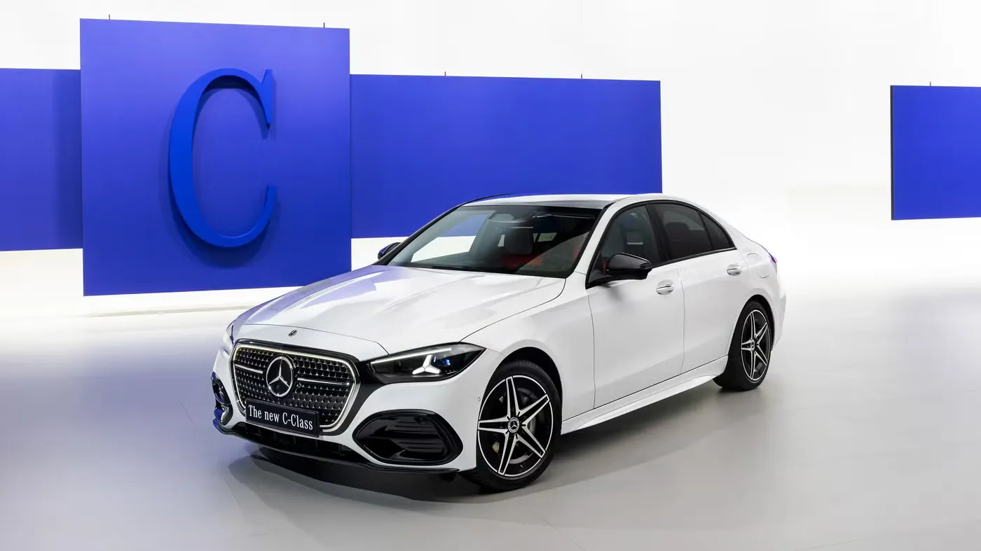 2027 Mercedes-Benz C-Class refreshed front three-quarter view with illuminated grille, AutoAkhbar branded image