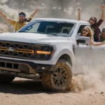 Ford F-150 Raptor-style off-road pickup truck driving on a desert trail at sunset