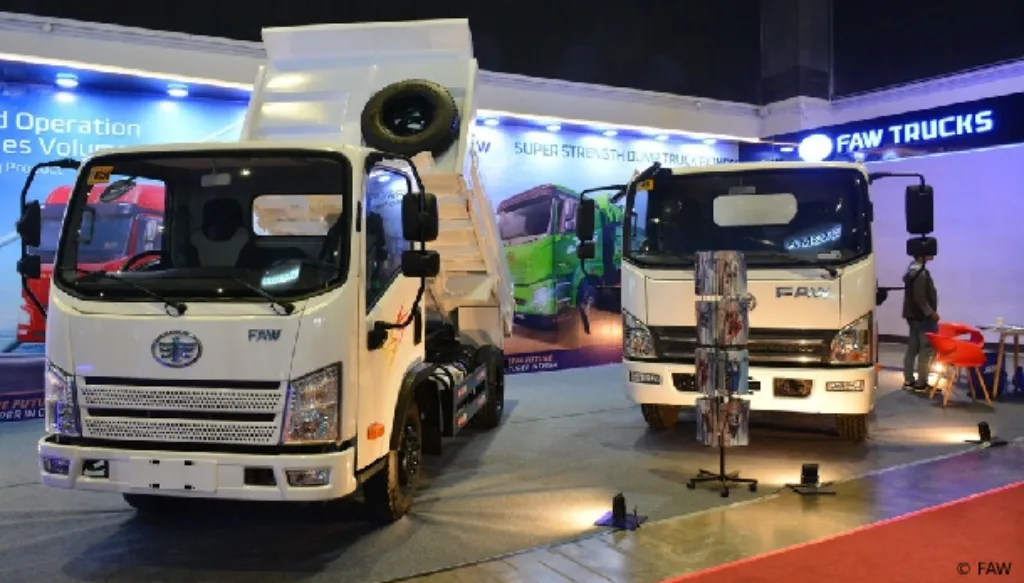 FAW light-duty dump trucks with raised tipper bed showcased at a commercial vehicle exhibition auto show.