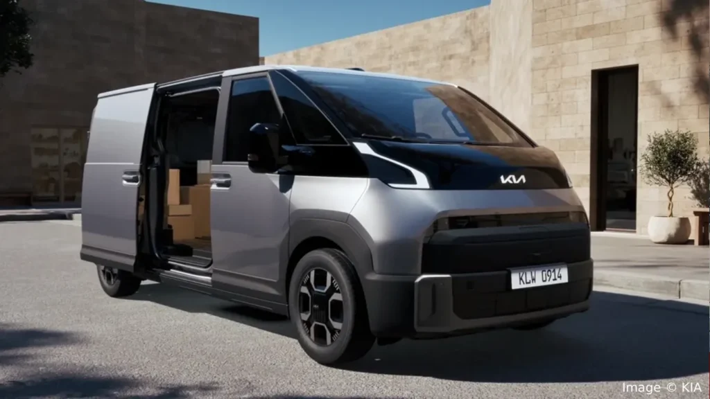Silver Kia PV7 electric commercial van parked outdoors with its sliding side door open, revealing the cargo interior design.